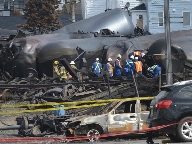 In this July 6, 2013 file-pool photo, emergency workers examine the aftermath of a train derailment and fire in Lac-Megantic, Quebec.