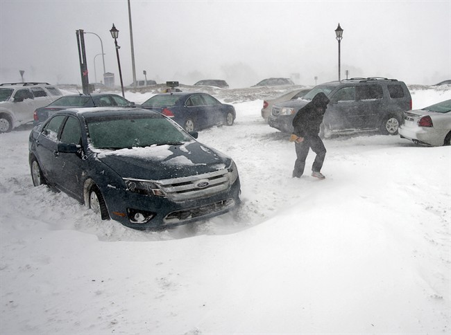 A stranded traveller crosses a parking lot at a service station in Borden-Carleton, Prince Edward Island on Sunday, Feb. 16, 2014.