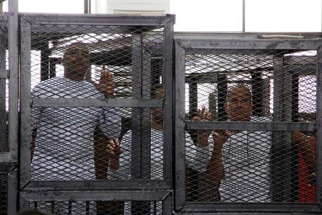 Al-Jazeera English bureau chief Mohamed Fahmy, left, producer Baher Mohamed, center and correspondent Peter Greste, right, appear in a defendant's cage in a courtroom along with several other defendants during their trial on terror charges, in Cairo, Egypt, Monday, March 31, 2014. His family said Friday they have met with Foreign Affairs Minister John Baird.
