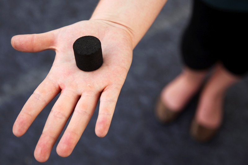 In this Friday, March 21, 2014 photo, an exhibitor displays a Biochar, a charcoal-like product made from human waste, used as cooking fuel or fertilizer, at the Reinvent The Toilet Fair in New Delhi, India. (AP Photo/Tsering Topgyal)