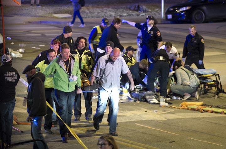 People carry a person who was struck by a car on Red River Street in downtown Austin, Texas, at SXSW on Wednesday March 12, 2014. (AP Photo/Austin American-Statesman/ Jay Janner).