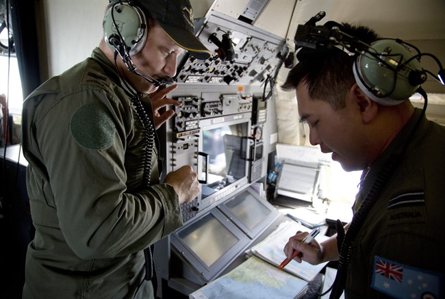 Crew members aboard a Royal Australian Air Force AP-3C Orion aircraft observe navigation maps as they search for missing Malaysian Airlines flight MH370 over the southern Indian Ocean, Thursday, March 27, 2014.