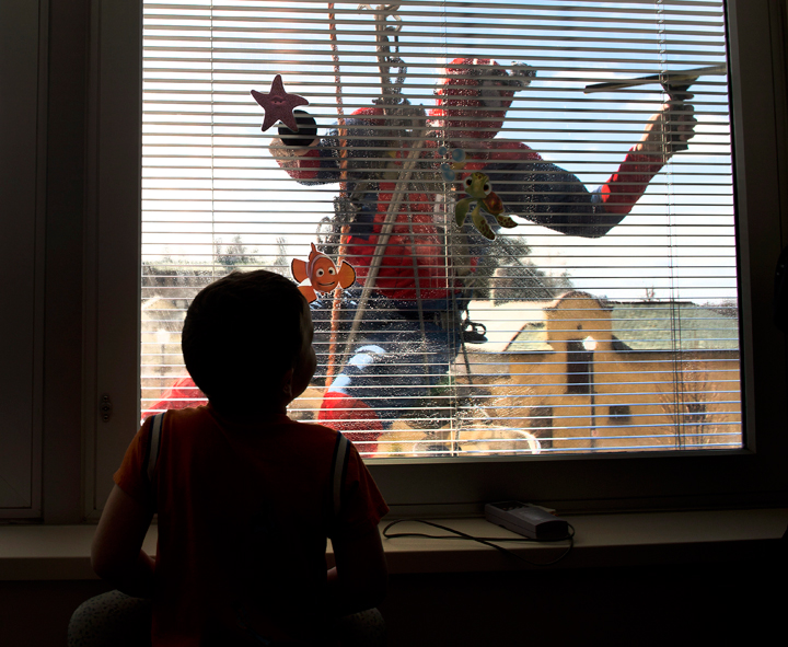 A young patient in the Paediatric Ward watches from his room as a window washer in a Spiderman costume washes the windows at Lakeridge Health in Oshawa, Ontario, on Friday, March 21, 2014.