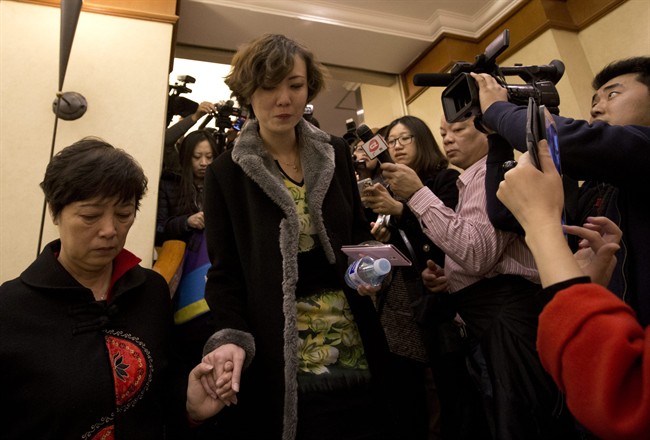 Chinese women, relatives of passengers aboard a missing plane, walk past the media outside a room at a hotel in Beijing, China Saturday, March 8, 2014.