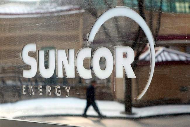 A pedestrian is reflected in a Suncor Energy sign in Calgary, Feb. 1, 2010. 