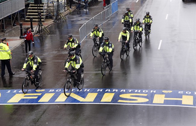 Police on bikes cycle across the Boston Marathon finish line prior to a remembrance ceremony for family members and survivors of the 2013 Boston Marathon bombing on Boylston Street in Boston, Tuesday, April 15, 2014.