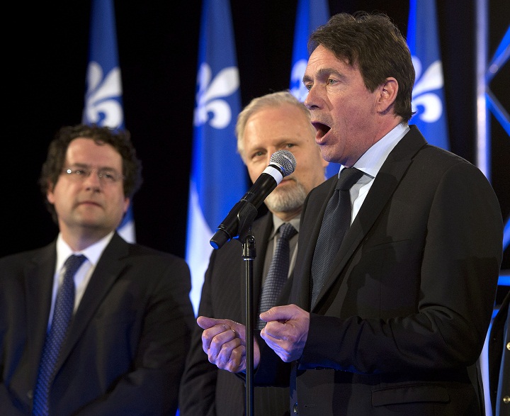 Parti Quebecois newly elected MNA Pierre Karl Peladeau, right, speaks to supporters as Ministers Bernard Drainville, left, and Jean-Francois Lisee look on Monday, April 7, 2014 in Montreal.