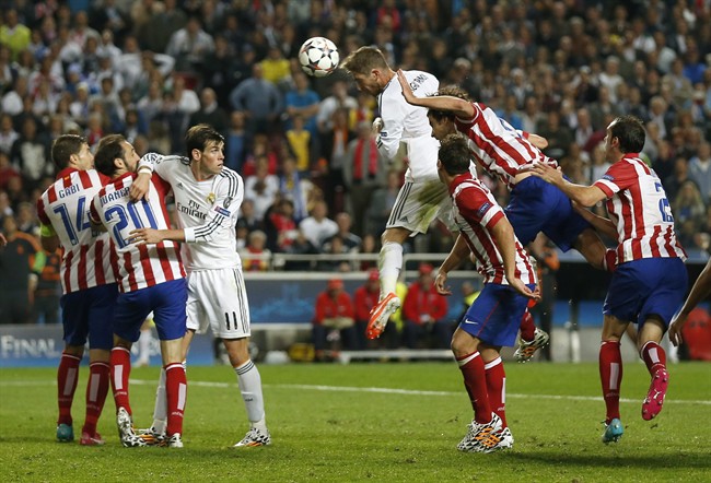 Real Madrid's Sergio Ramos, center, scores his side's first goal during the Champions League final soccer match against Atletico Madrid at the Luz Stadium in Lisbon, Portugal, Saturday, May 24, 2014. (AP Photo/Andres Kudacki).