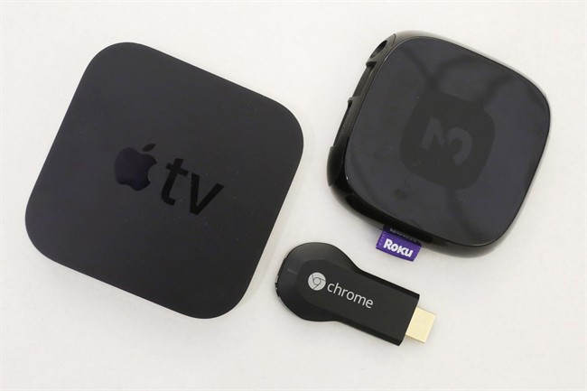 An Apple TV device, left, is shown alongside Google's Chromecast, center, and the Roku 2.