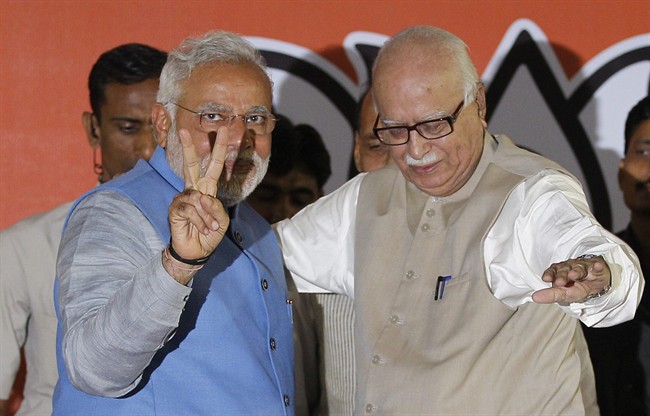 Opposition Bharatiya Janata Party (BJP) leader and India's next prime minister Narendra Modi, left, flashes the victory symbol standing next to senior party leader L.K. Advani at the party headquarters in New Delhi, India, Saturday, May 17, 2014.
