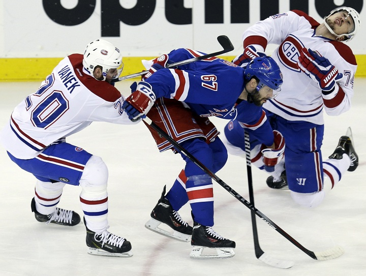 New York Rangers' Benoit Pouliot, center, commits a high sticking penalty against Montreal Canadiens' Alexei Emelin, right, while Thomas Vanek chases the puck during the first period of Game 4 of the NHL hockey Stanley Cup playoffs Eastern Conference finals, Sunday, May 25, 2014, in New York.