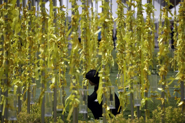 A woman attaches yellow ribbons for the victims and missing passengers of the sunken ferry Sewol at a group memorial altar in Seoul, South Korea, Wednesday, May 7, 2014. 