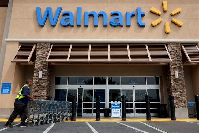 In this May 9, 2013 file photo, a worker pushes shopping carts in front of a Walmart store.