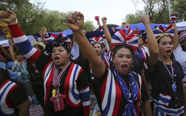 Anti-government protesters raise fists as they sing and listen to the national anthem during a gathering Thursday, May 22, 2014 in Bangkok, Thailand. Thailand\’s army chief announced a military takeover of the government Thursday, saying the coup was necessary to restore stability and order after six months of political deadlock and turmoil.