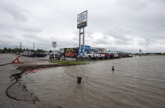 The ditches overflow with rain water near a car dealership in Melville, Saskatchewan on Sunday, June 29, 2014 . Highways are closing and communities are declaring states of emergency after a deluge of rain drenched southeast Saskatchewan and parts of Manitoba.
