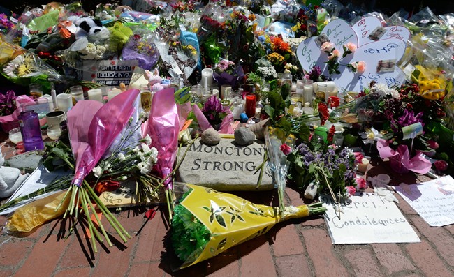 The memorial at the Codiac RCMP detachment in Moncton, N.B. is shown on Sunday, June 8, 2014., continues to grow. Hundreds of people running for three fallen Mounties put their race on hold on Sunday to shake the hands of officers as a memorial in front of an RCMP detachment was dismantled. THE CANADIAN PRESS/Sean Kilpatrick.
