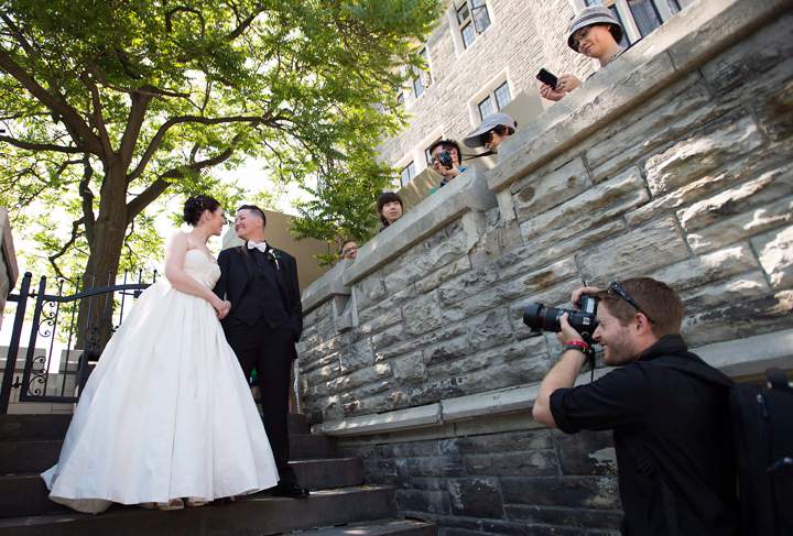 Dayna Murphy, left, and her partner Shannon St. Germain have their photo taken by tourists before joining over 100 gay couples in a mass wedding during World Pride 2014 at Casa Loma in Toronto, on Thursday, June 26, 2014.