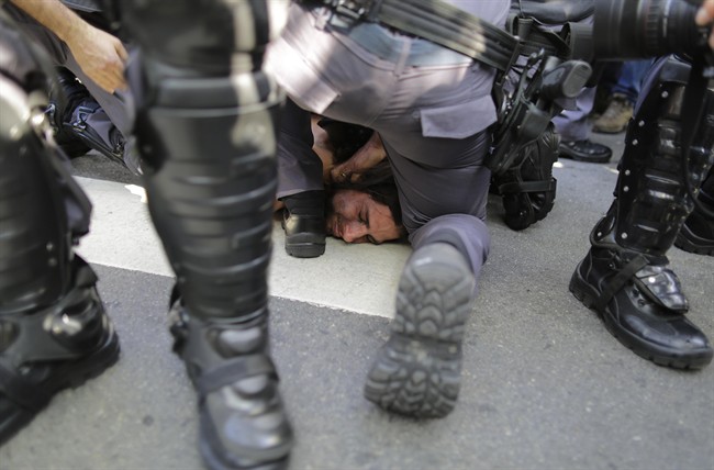 A protester is detained by police during a demonstration demanding better public services and protesting the money spent on the World Cup soccer tournament in Sao Paulo, Brazil, Thursday, June 12, 2014.