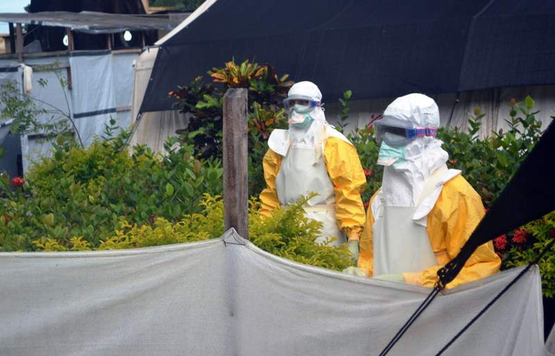 Members of Doctors Without Borders (MSF) wearing protective gear walk outside the isolation ward of the Donka Hospital, on July 23, 2014 in Conakry.  AFP PHOTO / CELLOU BINANI .