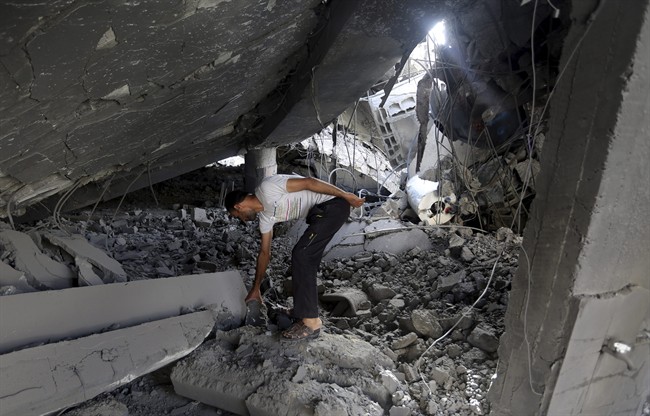 A Palestinian searches the ruins of the Al-Tawfeeq mosque after it was hit by an Israeli missile strike in the Nuseirat refugee camp, central Gaza Strip, Saturday, July 12, 2014.