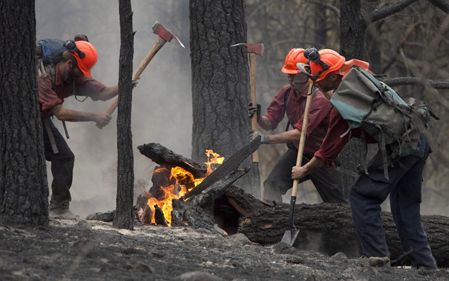 Firefighters tackle a flare up at the Smith Creek fire located on a hillside in West Kelowna, B.C., Saturday, during wildfire season.