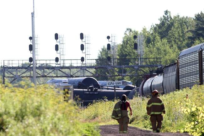 Fire fighters walk near the derailed train near Brockville, Ont., on Thursday July 10, 2014.