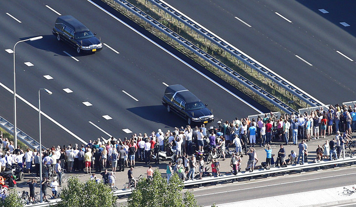 This aerial photo shows people watching from a bridge a convoy of hearses carrying coffins containing the remains of victims of the downed Malaysia Airlines flight MH17, driving from the Eindhoven Airbase to Hilversum on July 23, 2014.