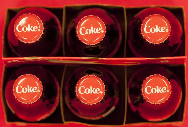 FILE - This July 15, 2013 file photo shows bottle tops of Coca-Cola 8 oz. bottles in Doral, Fla. The Coca-Cola Co. reports quarterly financial results before the market opens on Tuesday, July 22, 2014. (AP Photo/Wilfredo Lee, File)