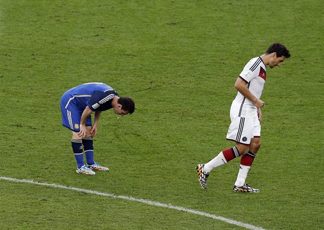 Argentina's Lionel Messi spits up as Germany's Mats Hummels walks by during the World Cup final soccer match between Germany and Argentina at the Maracana Stadium in Rio de Janeiro, Brazil, Sunday, July 13, 2014.