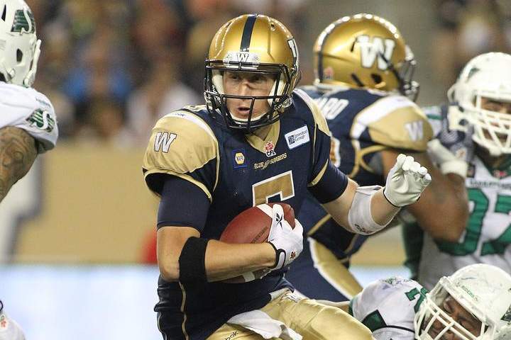 Quarterback Drew Willy #5 of the Winnipeg Blue Bombers is held by Trevor Guyton #92 of the Saskatchewan Roughriders at Investors Group Field on Thursday.