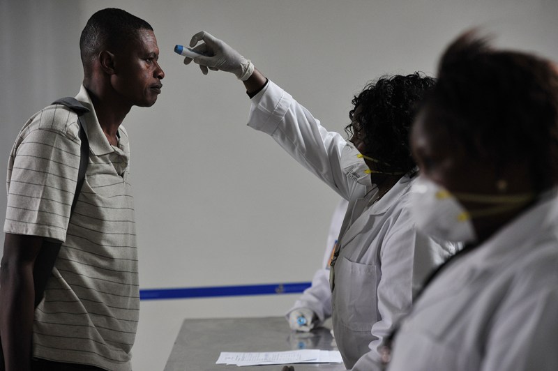 Kenyan health officials take passengers temperature as they arrive at the Jommo Kenyatta International Airport (JKIA) on August 14, 2014 in Nairobi. AFP PHOTO / SIMON MAINA .