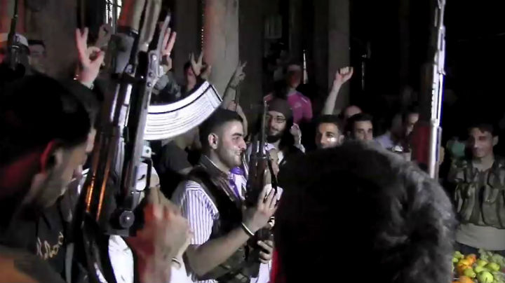 An image grab taken from AFP TV shows Syrian rebel sniper Abu Khaled (C) holding his gun as comrades celebrate during his wedding ceremony in the Saif al-Dawla district of the northern city of Aleppo on August 31, 2012.