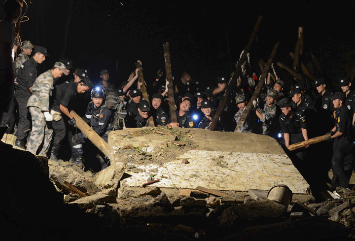 Rescue workers lift a wall that collapsed after a landslide hit Yingping village in Fuquan city in southwest China's Guizhou province Thursday Aug. 28, 2014. 