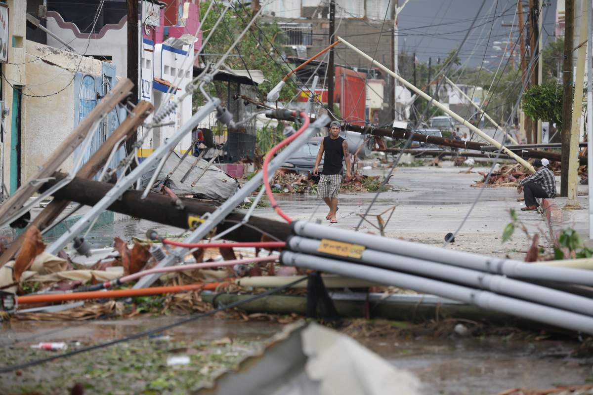 A man walks on a street where most power lines and light posts have been knocked down by Hurricane Odile, in Los Cabos, Mexico, Monday, Sept. 15, 2014. The storm, which made landfall near Cabo San Lucas the previous night as a powerful Category 3 hurricane, toppled trees, power poles and road signs along the main highway, which at one point was swamped by rushing floodwaters. (AP Photo/Victor R. Caivano).