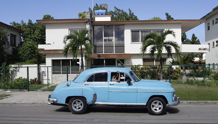 In this Friday Nov. 18, 2011 photo, a classic car drives in front of the headquarters of the firm Coral Capital Group in Havana. The government has given no information on probes of the investment firm Coral Capital Group, led by a Briton, Tri-Star Caribbean and Tokmakjian Group, two car dealerships run by Canadians.