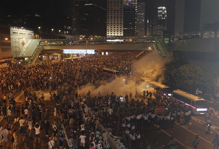Riot police use tear gas against protesters after thousands of people blocked a main road at the financial central district in Hong Kong, Sunday, Sept. 28, 2014.