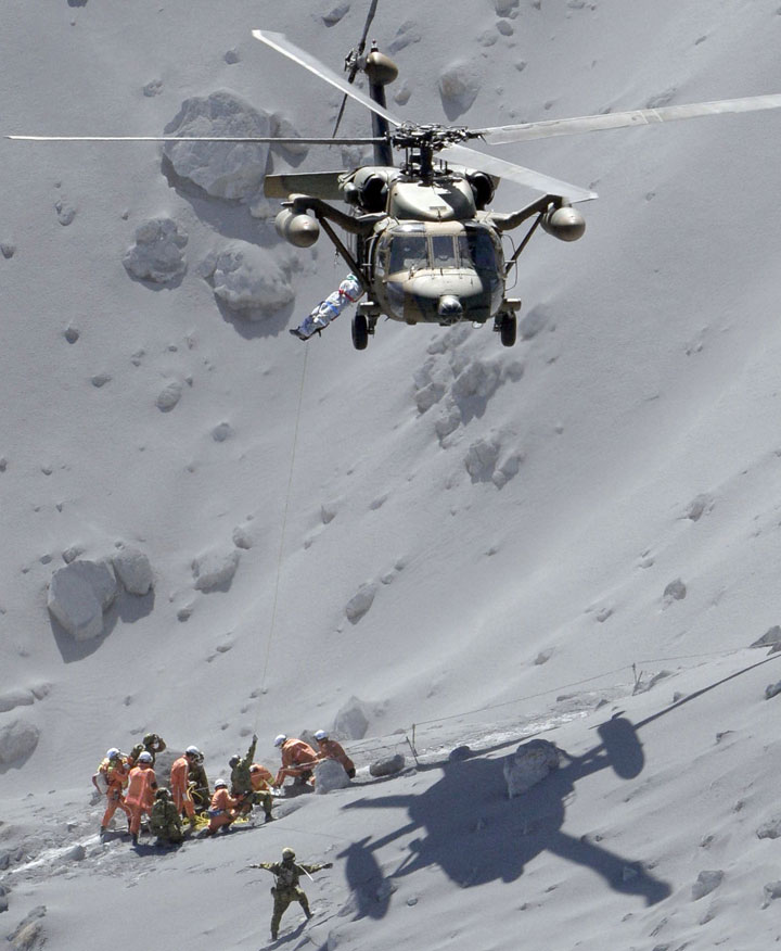 Rescuers help an injured person on Mount Ontake in central Japan, Sunday, Sept. 28, 2014.