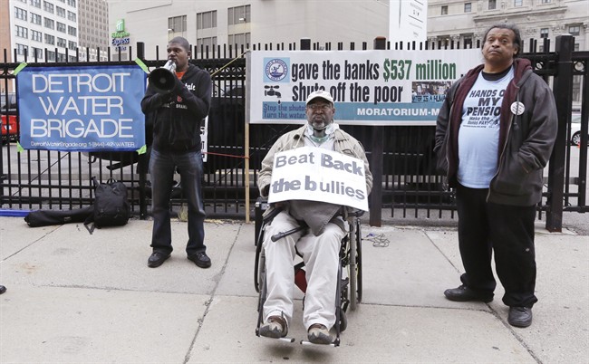 Demeeko Williams, left, of the Detroit Water Brigade talks into a megaphone during a rally outside federal courthouse in Detroit, Monday, Sept. 22, 2014. 