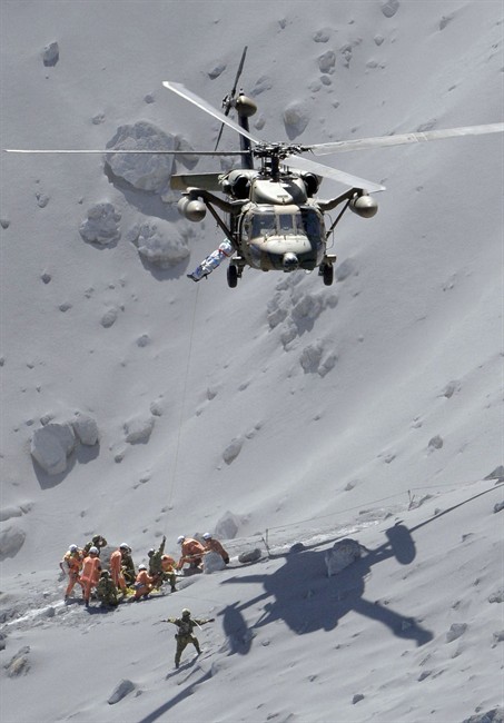 Rescuers help an injured person on Mount Ontake in central Japan, Sunday, Sept. 28, 2014. Mount Ontake erupted shortly before noon Saturday, spewing large white plumes of gas and ash high into the sky and blanketing the surrounding area in ash.