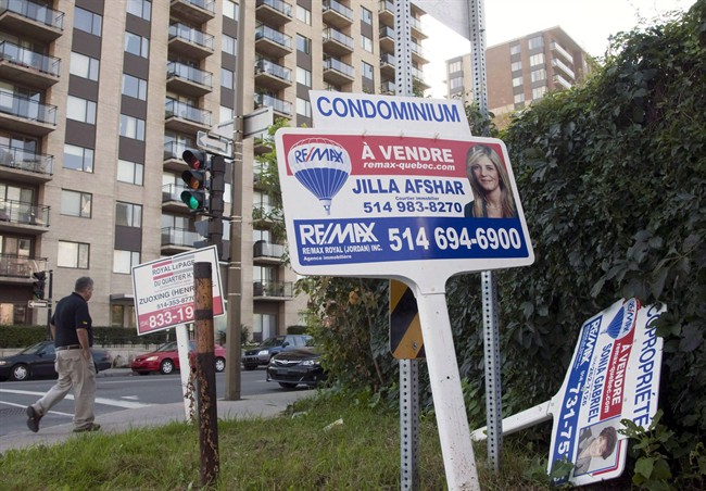 A sale signs stand in front of a condominium.