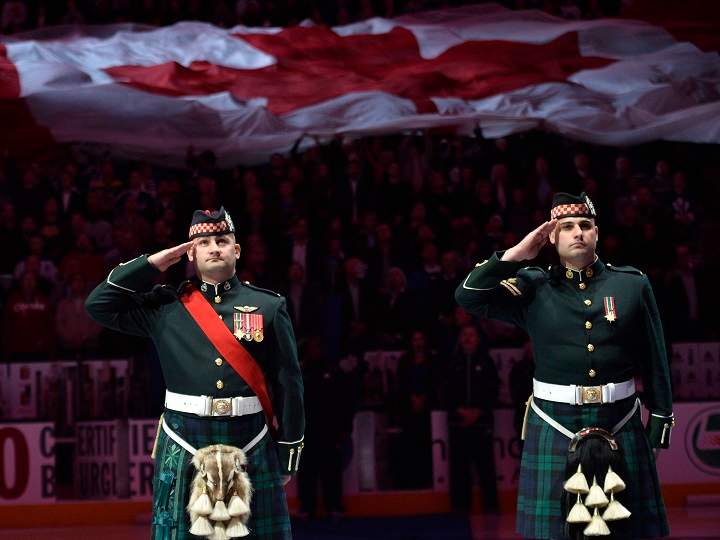 Members of the Canadian Forces salute as they take part in a pre-game ceremony honoring the two fallen soldiers in the recent attacks on Canadian soil before NHL hockey action between the Toronto Maple Leafs and the Boston Bruins.