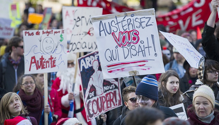 Protesters hold up signs during an anti-austerity demonstration in Montreal Friday, October 31, 2014.
