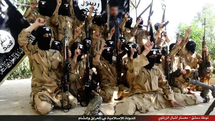 Children pose with guns in front of ISIS flags at a purported training camp in Syria. The image comes from a propaganda video released by ISIS.