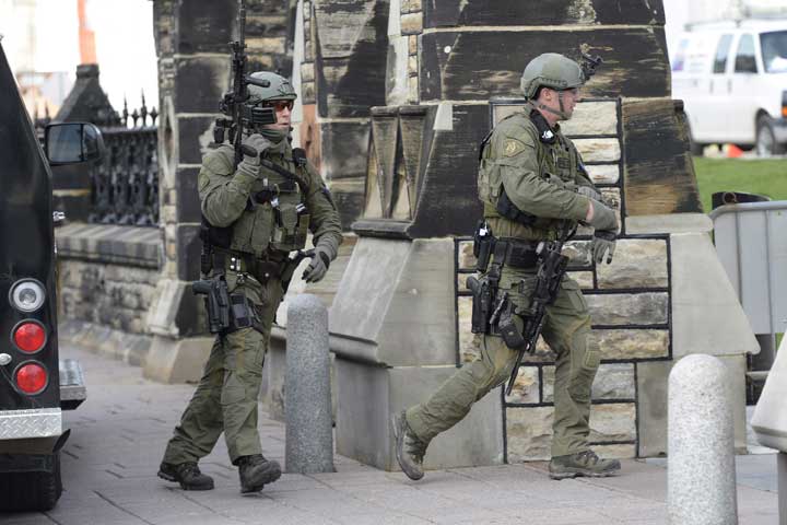 RCMP intervention team members walk past a gate on Parliament hill in Ottawa Wednesday Oct.22, 2014. 