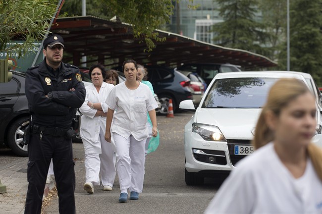 Hospital staff walk out past police guarding the entrance to protest outside the Carlos III hospital in Madrid, Spain, Tuesday, Oct. 7, 2014 where a Spanish nurse who is believed to have contracted the Ebola virus from a 69-year-old Spanish priest is being treated after testing positive for the virus.