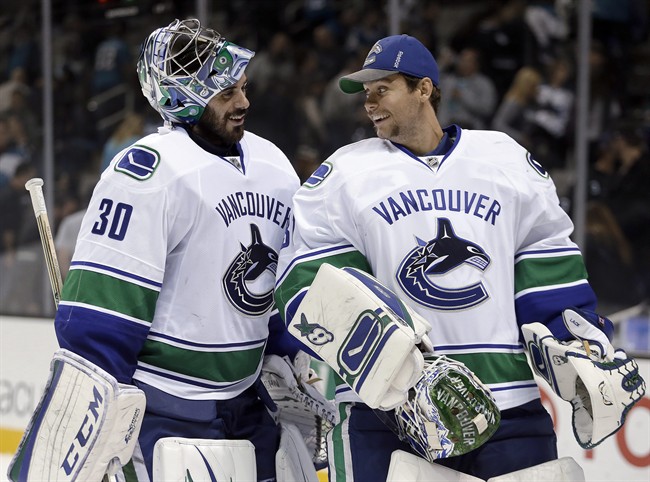 Vancouver Canucks goalies Ryan Miller, left, and Eddie Lack smile at the end of an NHL hockey game against the San Jose Sharks on Thursday, Nov. 6, 2014, in San Jose, Calif. Vancouver won 3-2.
