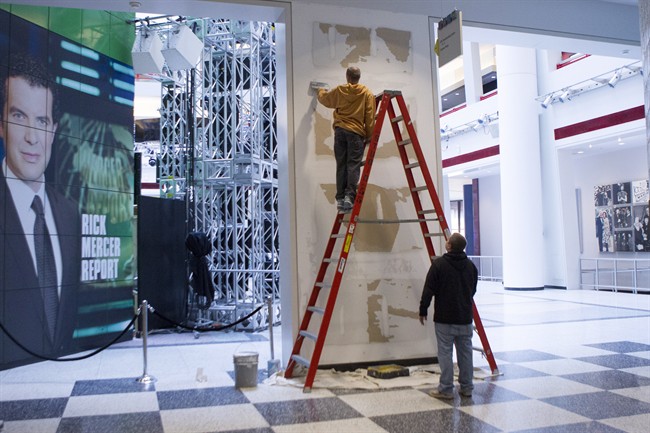 Workers scrape a wall which had a publicity photo of former CBC radio host Jian Ghomeshi in the broadcasting corporation's Toronto offices on Monday October 27, 2014.