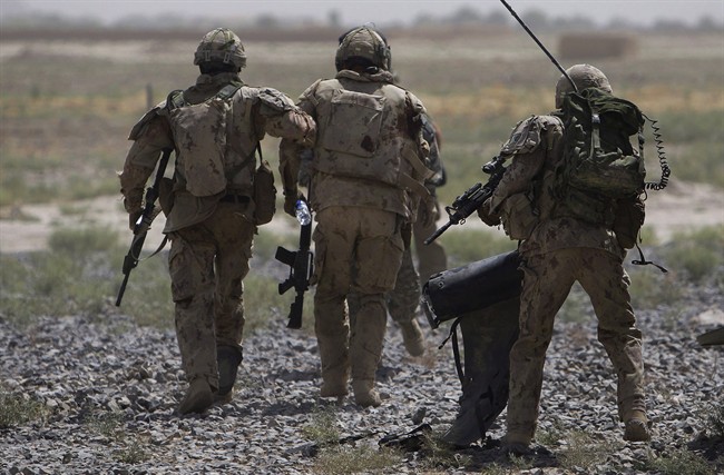 Canadian soldiers help a comrade, center, getting on a helicopter after he was injured in an IED blast during a patrol outside Salavat, Afghanistan, Monday, June 7, 2010.