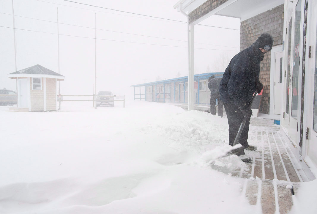 FILE - Alex Mullin shovels snow from the lodge entrance of Poley Mountain ski resort, on Saturday Feb. 9, 2013 in Waterford, N.B.