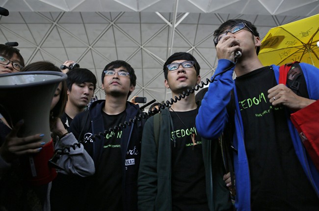 Hong Kong Federation of Students leader Alex Chow, left, committee members Nathan Law, centre, and Eason Chung speak to supporters before attempting to travel to Beijing, at Hong Kong International Airport Saturday, Nov. 15, 2014.